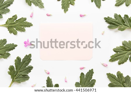Craft paper card with flower and green leaves on white background. Overhead view. Flat lay, top view.