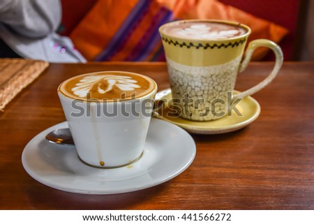 Two cups of cappuccino with latte art on wood table.  Royalty-Free Stock Photo #441566272