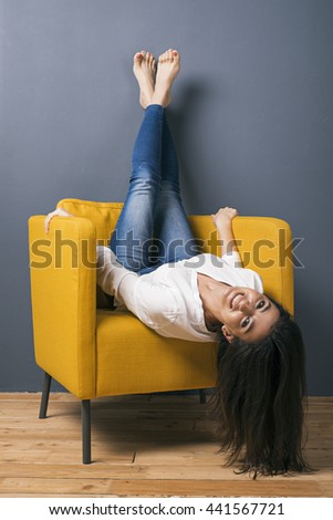 Portrait of upsidedown Armenian girl on arm-chair smiling at camera