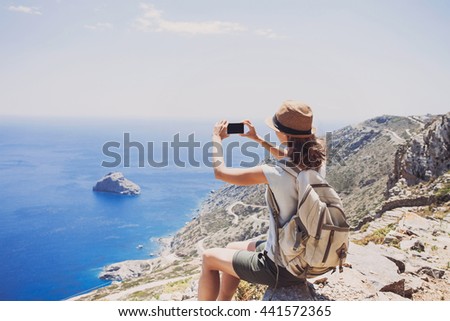 Hiking woman using smart phone taking photo, travel and active lifestyle concept