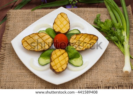 Baked potatoes with vegetables on the background color. Wooden table. Close-up