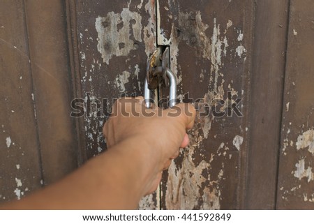 Locked vintage wooden door for safety with a hand of person