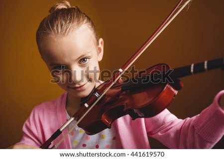 Girl playing the violin on yellow background