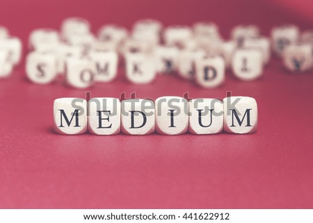 Medium word written on wood cube with red background