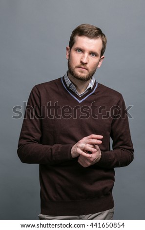 Young bearded  man in casual clothes standing  in the studio, and gesturing with his hands, business style