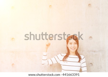 Woman thinking against concrete wall