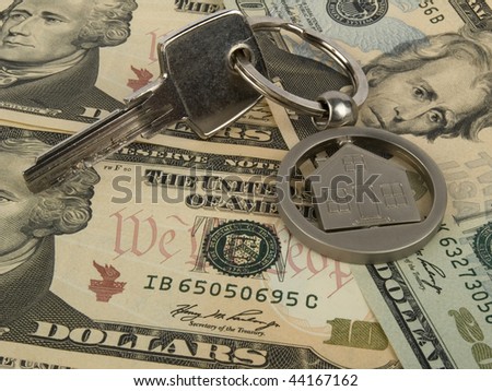 House key on pile of dollar banknotes