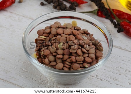Raw lentils in the bowl on wood background