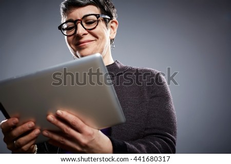 Studio portrait of mature businesswoman reading digital tablet