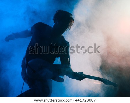Silhouette of guitar player on stage. Dark background, smoke, spotlights Royalty-Free Stock Photo #441723007