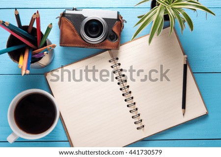 Office desk table with notepad, camera, cup of coffee and flower. top view