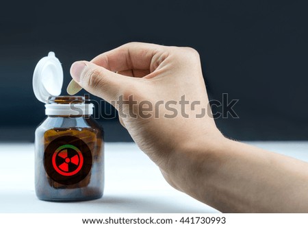 Toxic sign on tablets bottle with hand holding tablet 