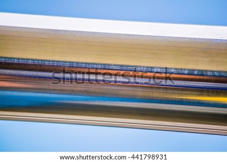 detail of a metal bar reflecting color strips on sun