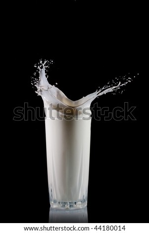 Glass with pouring milk isolated on black