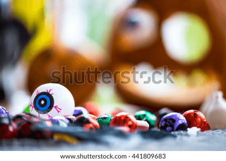 Close up of Plastic Eye and Sweets with Pumpkin Jack-o-Lantern on the Background, Halloween Concept