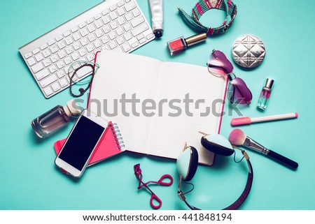 Still life of fashion woman, girl,student on  trendy blue background. Overhead of essentials for modern young person .Note book, nail polish, lipstick,  powder, glasses, watch,  stylish 
headphones. Royalty-Free Stock Photo #441848194