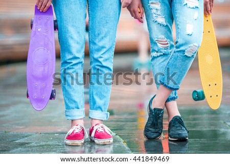 Two hipster girls with skateboard outdoors in sunset light. Closeup skatebords in female hands. Active sporty women having fun together in skate park.