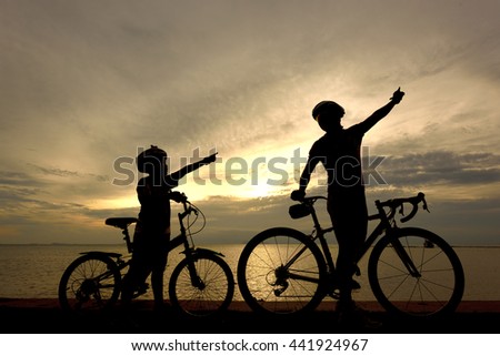 Biker family silhouette on the beach at sunset.

