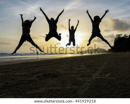 jumping on the beach at sunset in silhouette