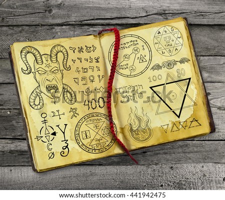 Old magic book with Devil, pentagram and mystic symbols lying on wooden table. Halloween still life, black ritual with occult and esoteric signs