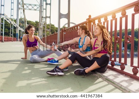 Three sportive pretty women having rest after successful jogging workout outdoors. Cute female running partners resting after hard physical activity Sporty friends portrait