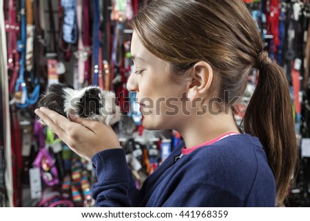 Cute Girl Holding Small Guinea Pig At Store