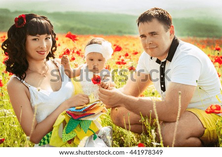 happy family of three having fun and smiling outdoor on the poppy field . Happy young family spending time together outside. Happy mother, father and daughter