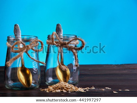 Two empty jar with bronze spon inside scattered oat flakes and kiwi.Wooden and cyan background.Free space.