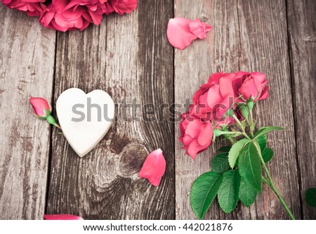 Flowers. Bouquet of red roses with Heart of marble on wooden table. Vintage Valentine Floral background. Toned image in retro style.