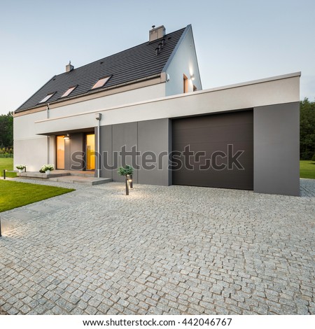 External view of stylish house with big garage and stone driveway