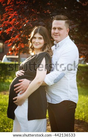 Portrait of a beautiful pregnant wife and husband nature in the Park