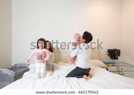 Female couple on bed playing with baby and toddler daughters