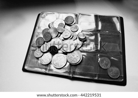 Different countries coins at umismatics album. Black and white photo