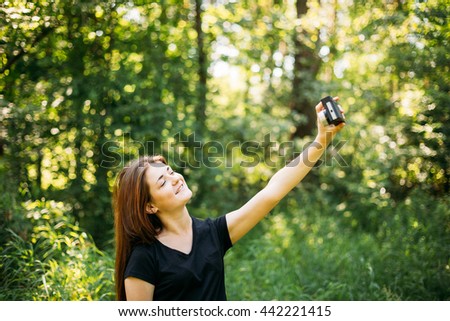 Happy Red-haired Caucasian Girl Young Woman Photographer Taking Selfie And Pictures The Old Retro Vintage Film Camera In Summer Green Forest. Girl Dressed In A Black T-shirt
