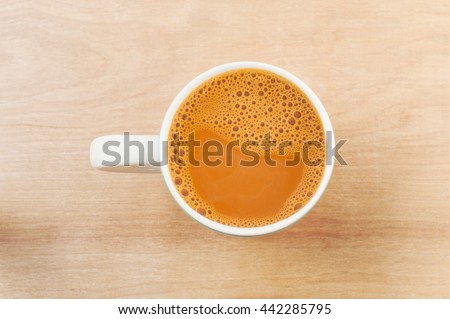 Hot milk tea in a white cup on wooden table Royalty-Free Stock Photo #442285795