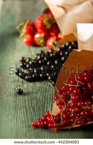 berries (strawberry, mulberry, currant) wrapped in paper on a green wooden table
