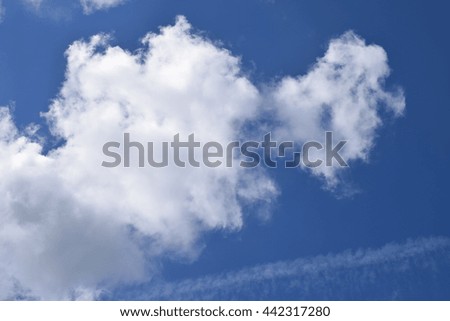A fluffy puffy cloud formation, white and bright in a deep blue sky, calming, relaxing, welcoming and peaceful.