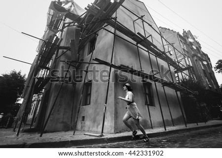 stylish woman hipster running and having fun on old european streets in sunny morning, black and white photo