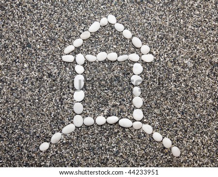 Small house symbol collected from a sea pebble on sand
