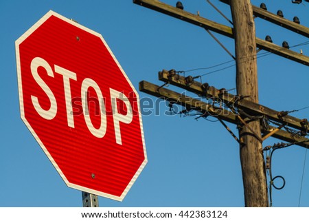 Stop sign with telephone pole and vibrant blue skies in background.
