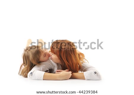 Kissing mother and her little daughter in white lying on white background.