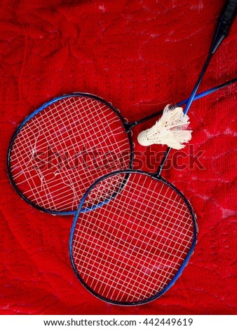 Old wooden badminton rackets and shuttlecock on red background