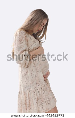 Silhouette pregnant woman looking at belly and strokes in a bright dress with long blond hair on white background
