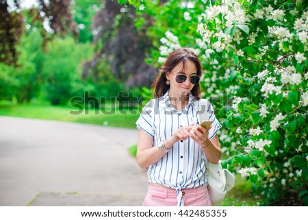 Tourist girl sending messgae by smartphone on summer holidays. Young attractive tourist with mobile phone outdoors enjoying holidays travel destination in tourism and exploring concept