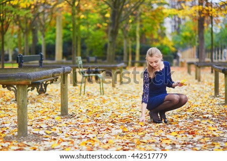 Beautiful young woman in blue dress in the Luxembourg garden of Paris on a fall day