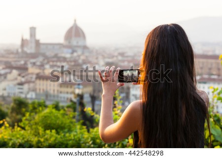 Young Teen at sunset in Florence takes a picture at the panorama with the smartphone.