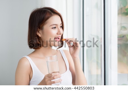 Close Up Of Happy Asian Woman Taking Pill With  Omega-3 And Holding A Glass Of Fresh Water In Morning. Vitamin D, E, A Fish Oil Capsules. Nutrition. Healthy Eating, Lifestyle. Royalty-Free Stock Photo #442550803