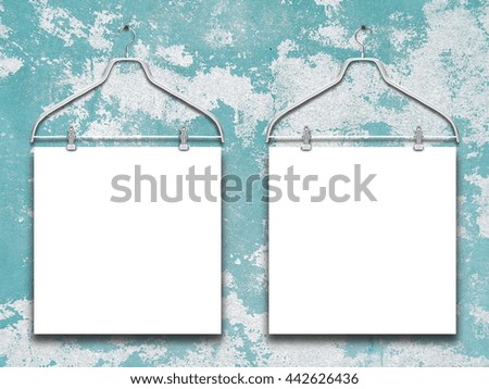 Close-up of two square blank frames hanged by clothes hanger against blue and white scratched wall background