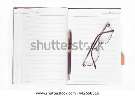 Glasses on notebook and pen on white background.