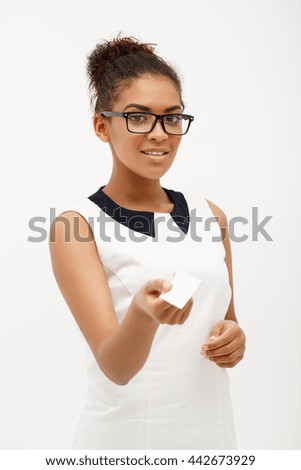 Portrait of young successful african business lady looking at camera, smiling, holding  business card over white background.